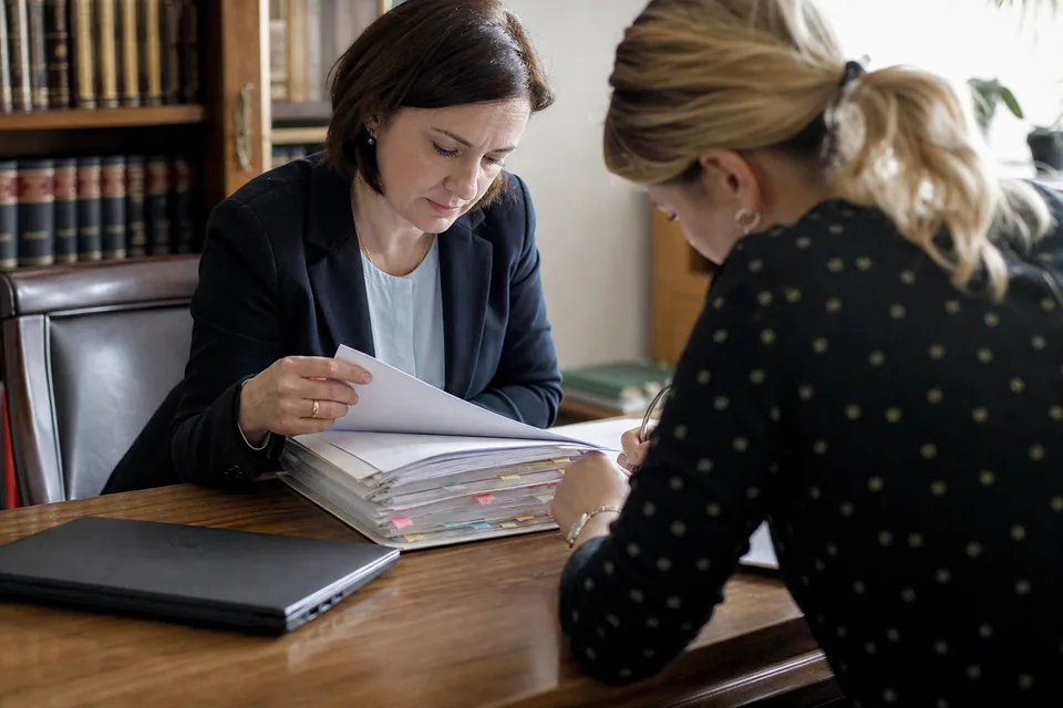 Prawniczka i właścicielka firmy przeglądają akta sprawy o zapłatę przy stole konferencyjnym